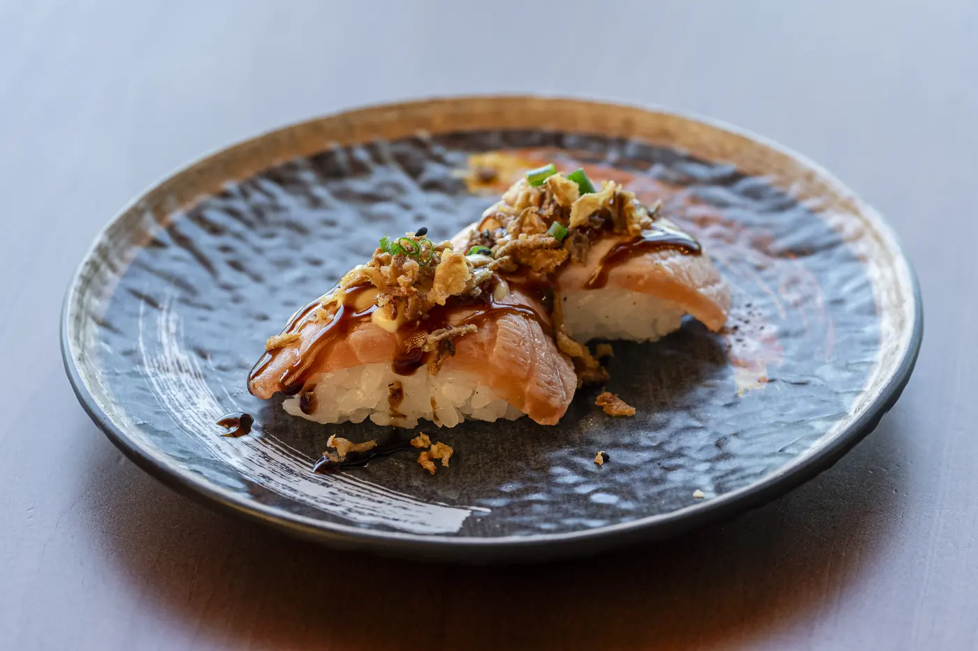 Nigiri de salmón aburi teriyaki con cebolla crujiente y cebollino